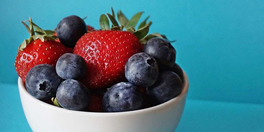 White bowl with blueberries and strawberries.