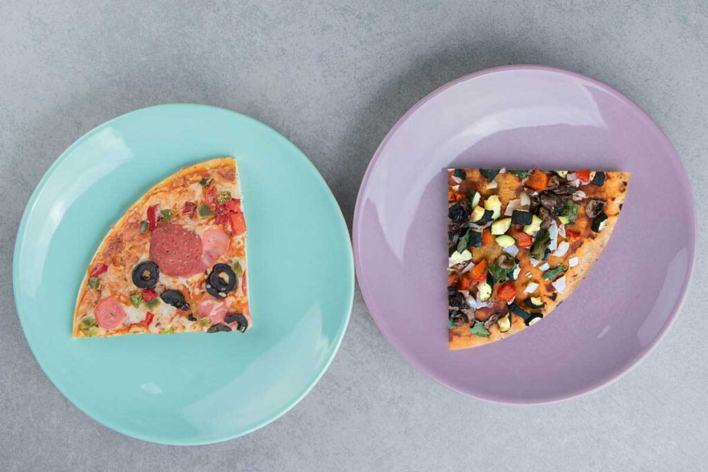 Two plates, one with frozen pizza slice one with homemade veggie pizza slice.