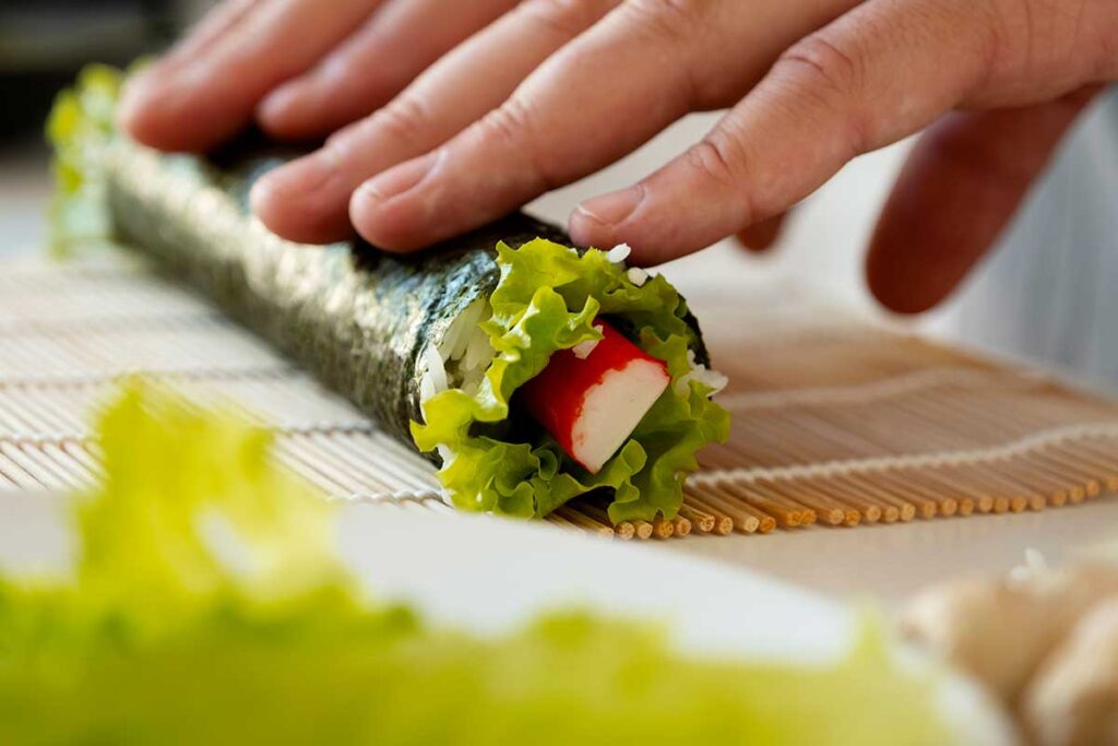 Close up of someone rolling a nori wrap full of veggies.