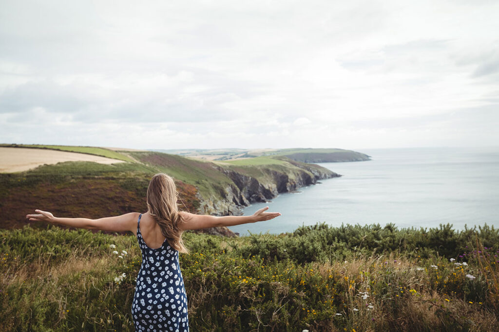 Rear view woman standing with arms outstretched.