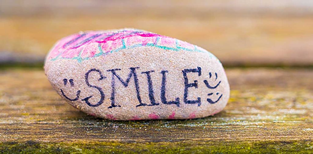 Rock with the word "Smile" written on it and 3 smiley faces.