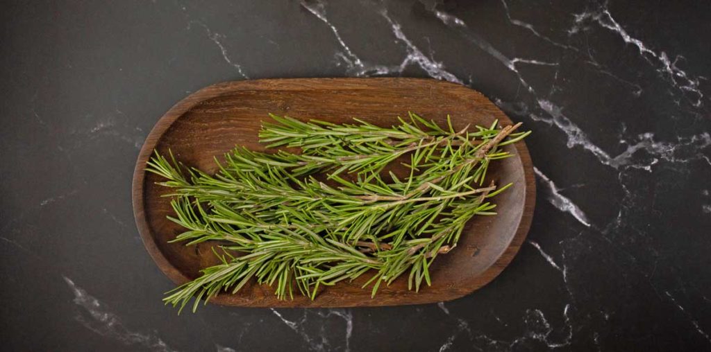 Rosemary sprigs in wooden dish.