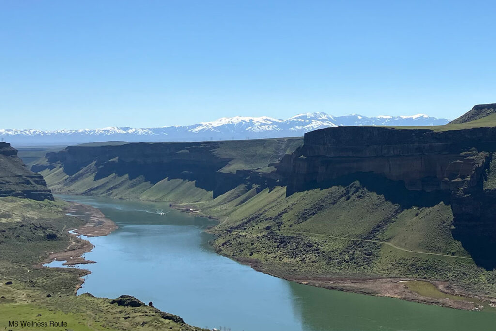 Scenic view overlooking canyon with river and mountains in the background.