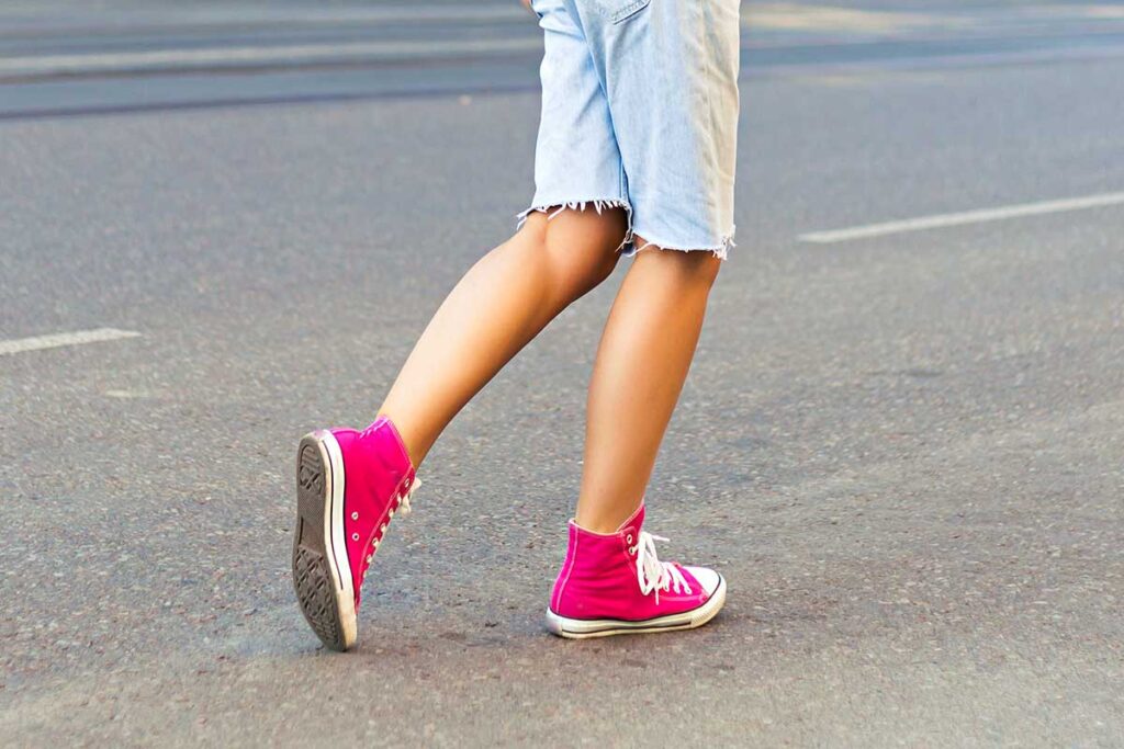 Healthy young woman walking down the street in pink sneakers.