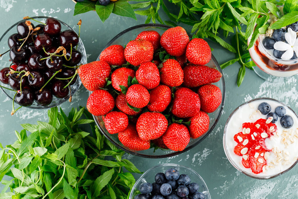 Dessert with strawberry, blueberry, mint, cherry in vase and goblet.