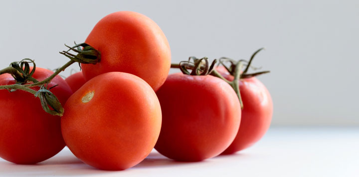 Six tomatoes on a vine.