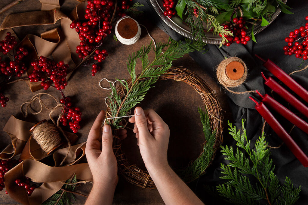 Top view of woman's hands assembling Christmas wreath.