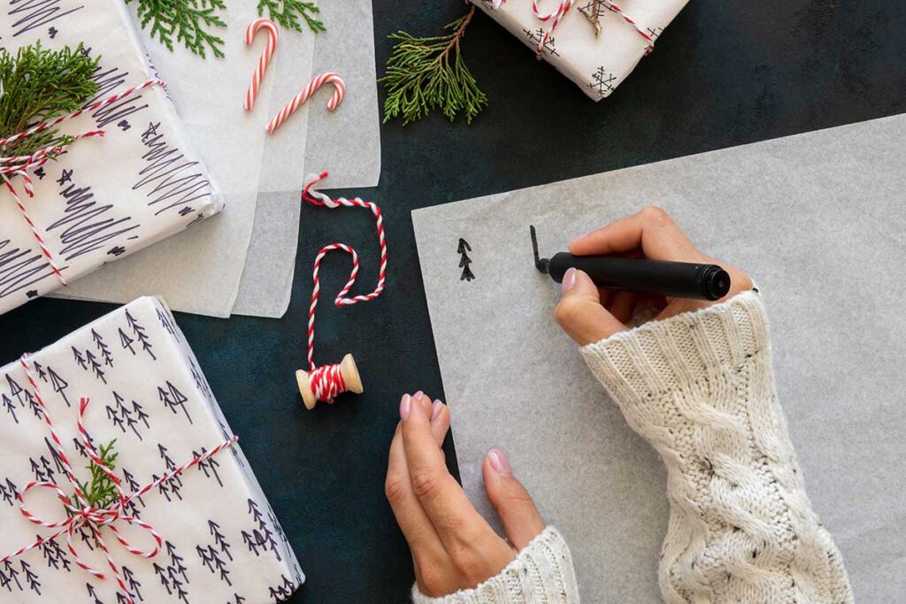 Top view of hands drawing Christmas trees on paper.