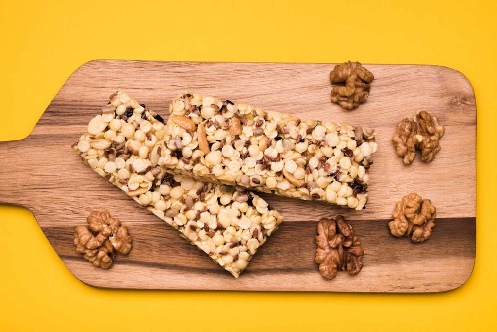 Top view of nuts and seeds bars on a cutting board and yellow background.