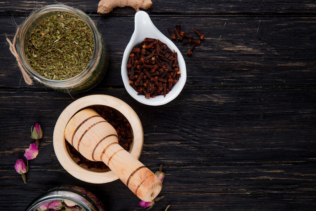 Top view of various herbs and spices with mortar and pestle.