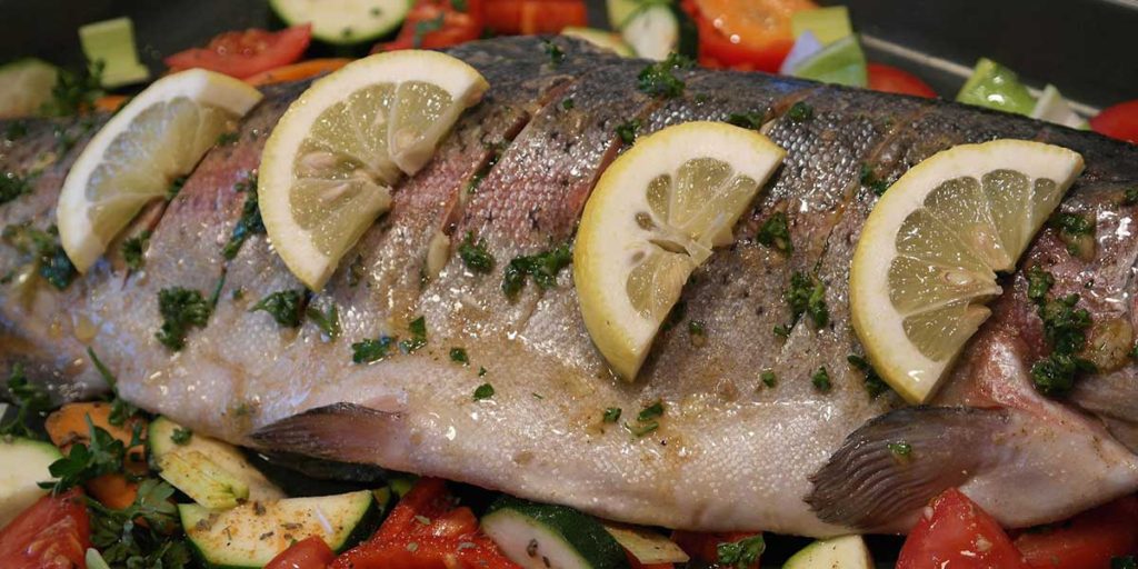 Trout dinner on veggies with lemon slices.