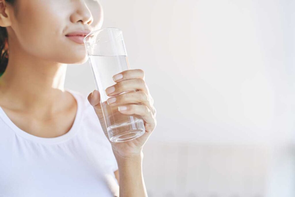 Unrecognizable woman carrying glass of water to mouth.