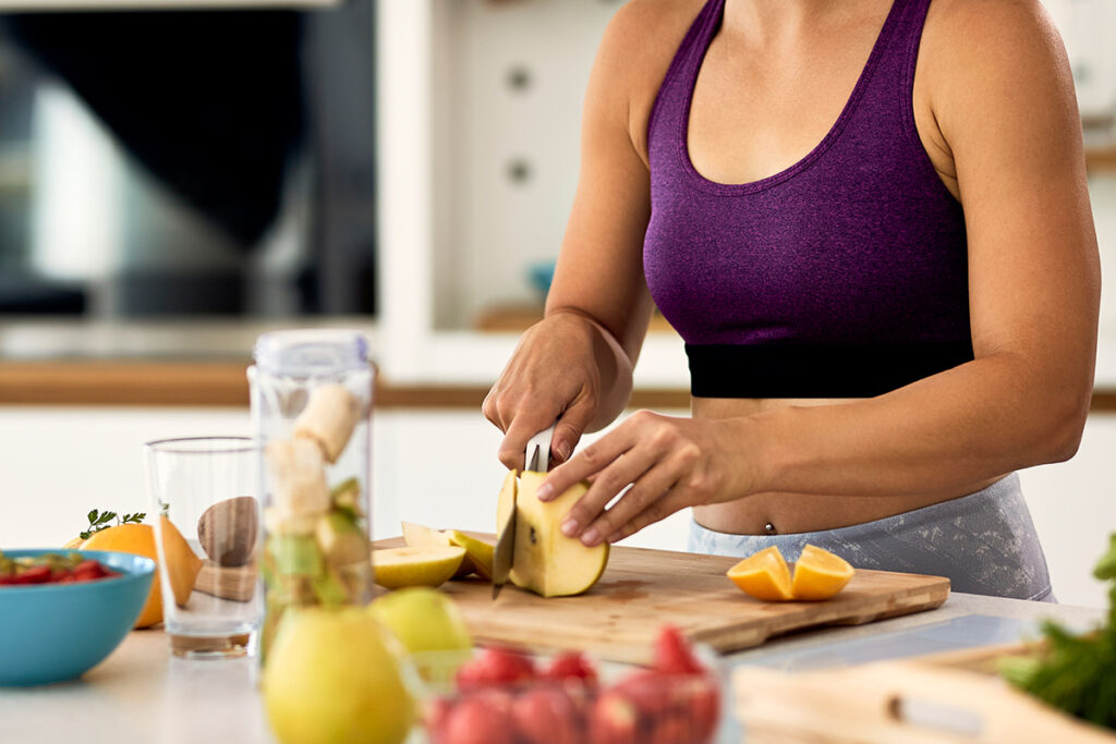 Woman cutting fruit while preparing healthy meal in the kitchen.