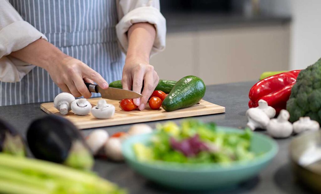 Woman in blue and white striped apron cutting vegetables.