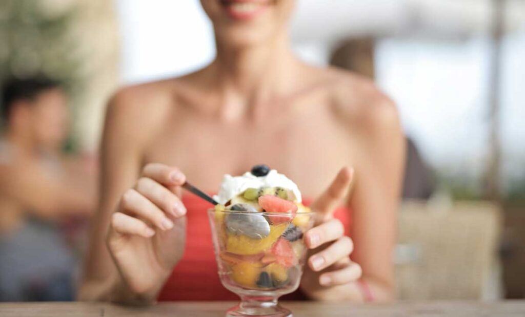 Woman eating a fruit dessert.