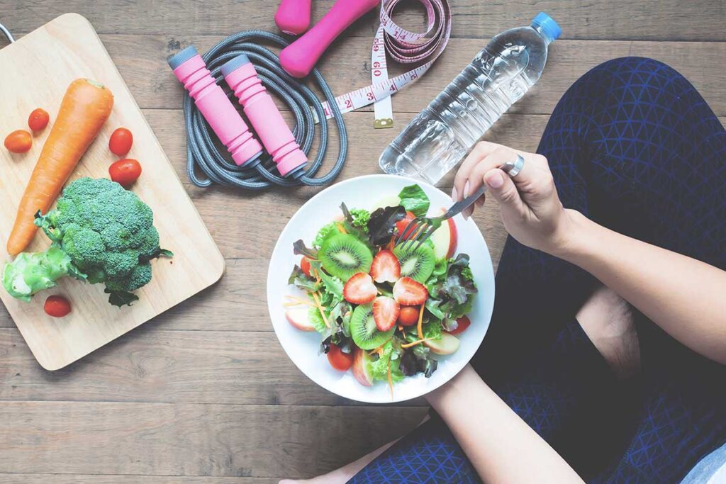 Woman sitting on floor eating healthy with jumprope and water bottle. 