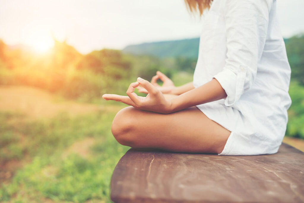 Woman in yoga pose meditating and making a zen symbol with her hands.