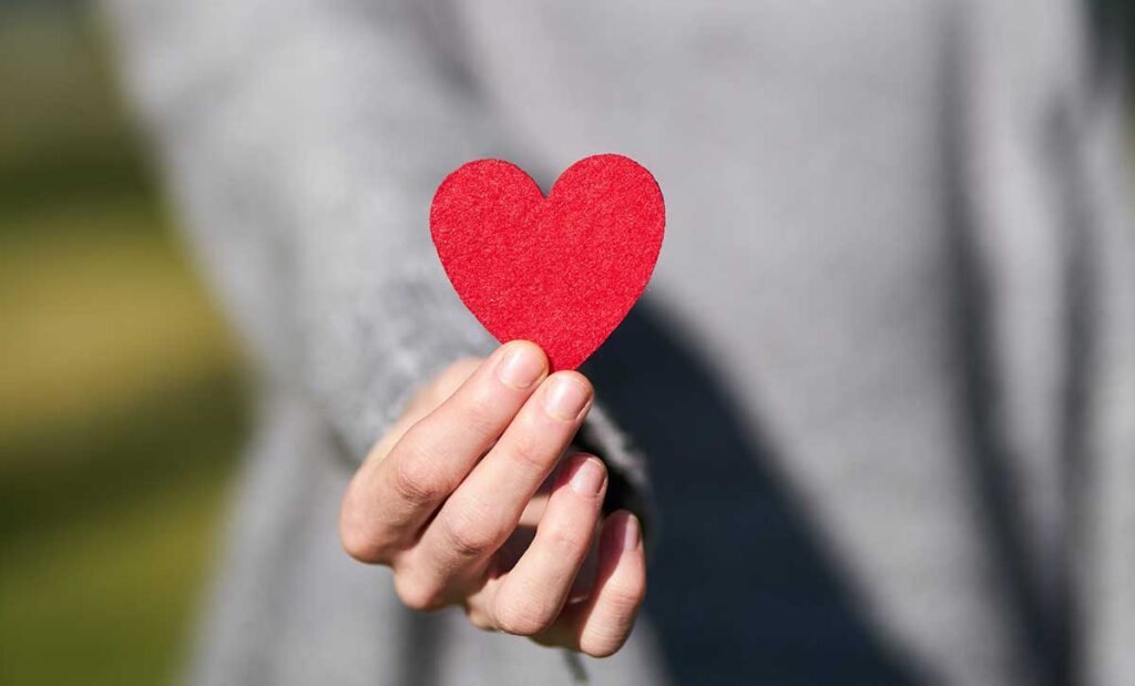 A woman holding a red paper heart.