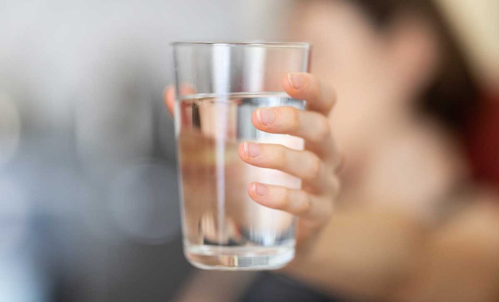 Woman holding up glass of water.