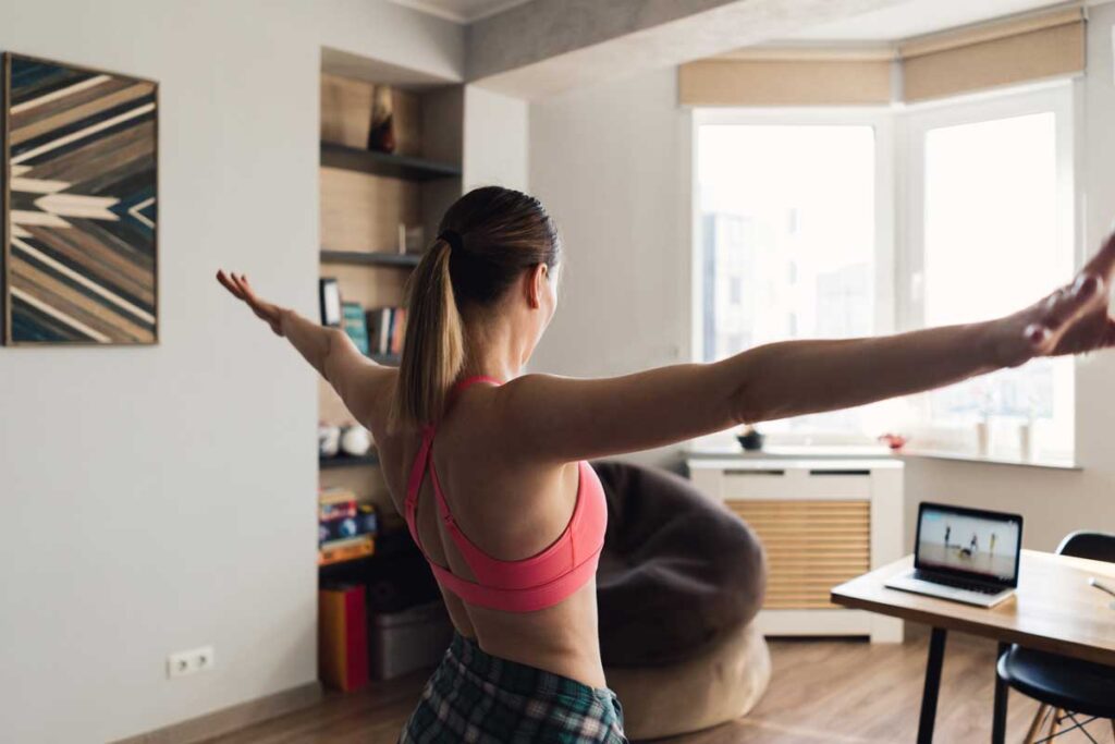 Woman at home exercising following a video on her laptop.