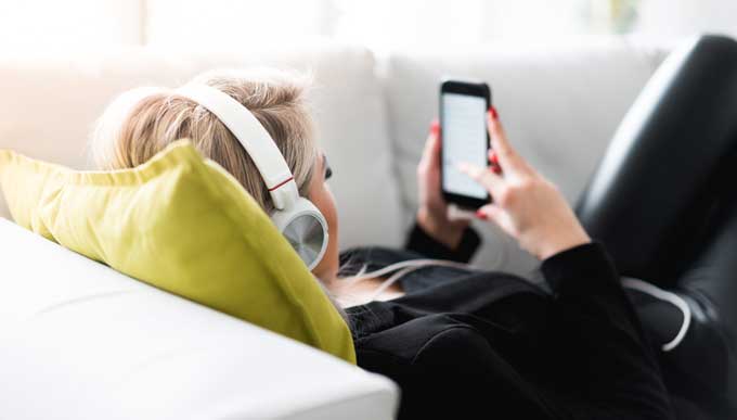 Young woman listening to music on sofa.