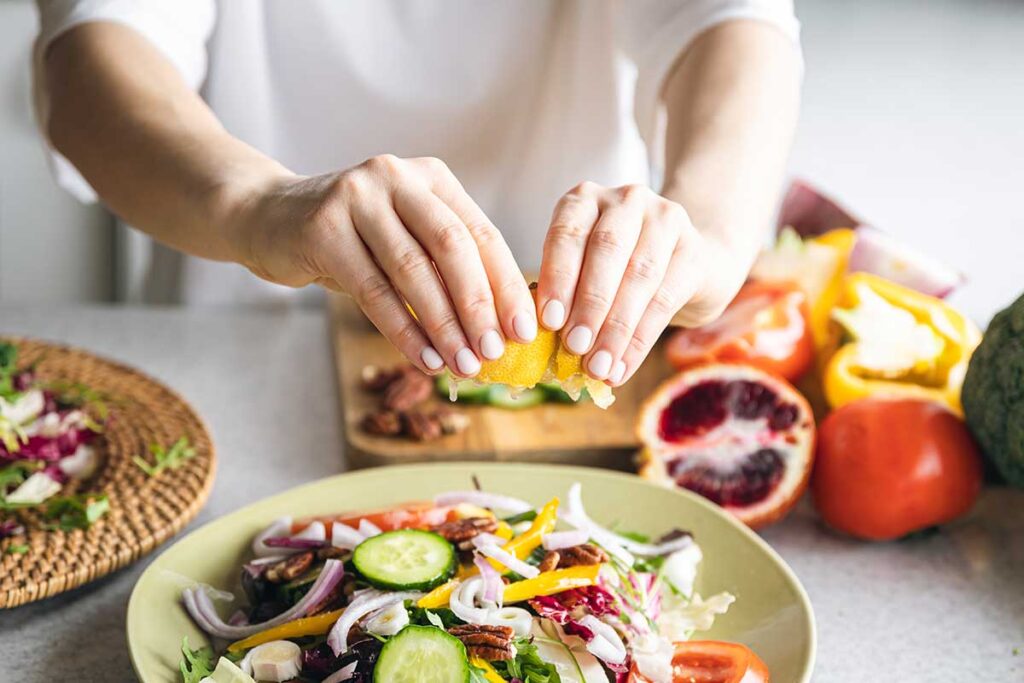 Close up of woman making fresh vegetable salad.