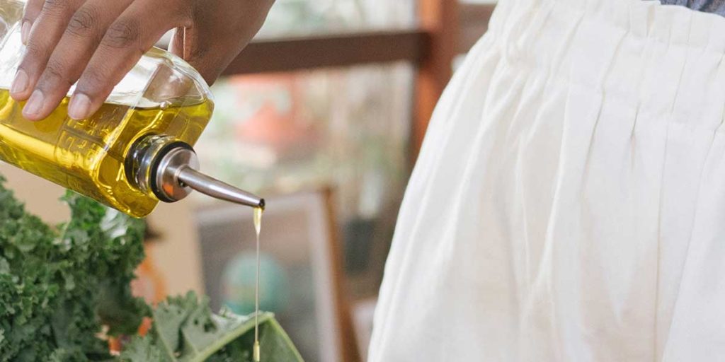 Soman pouring olive oil.