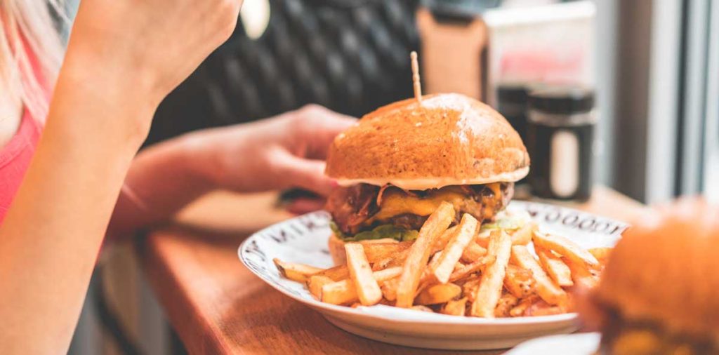 A woman preparing to eat a hamburger and fries.