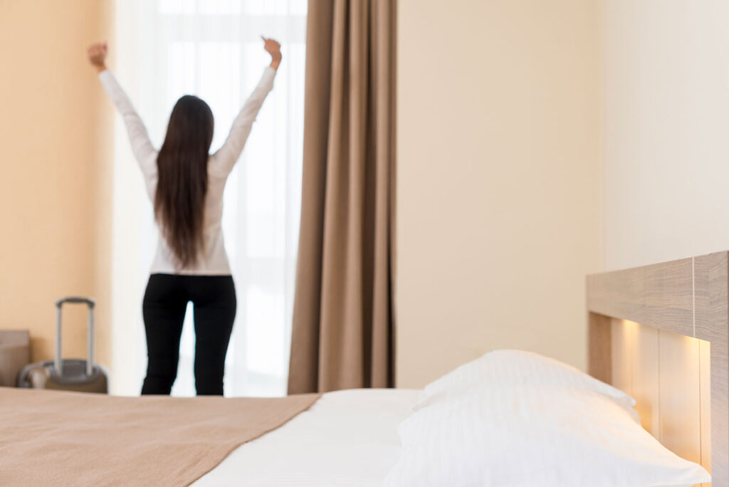 Woman waking up refreshed in bedroom.