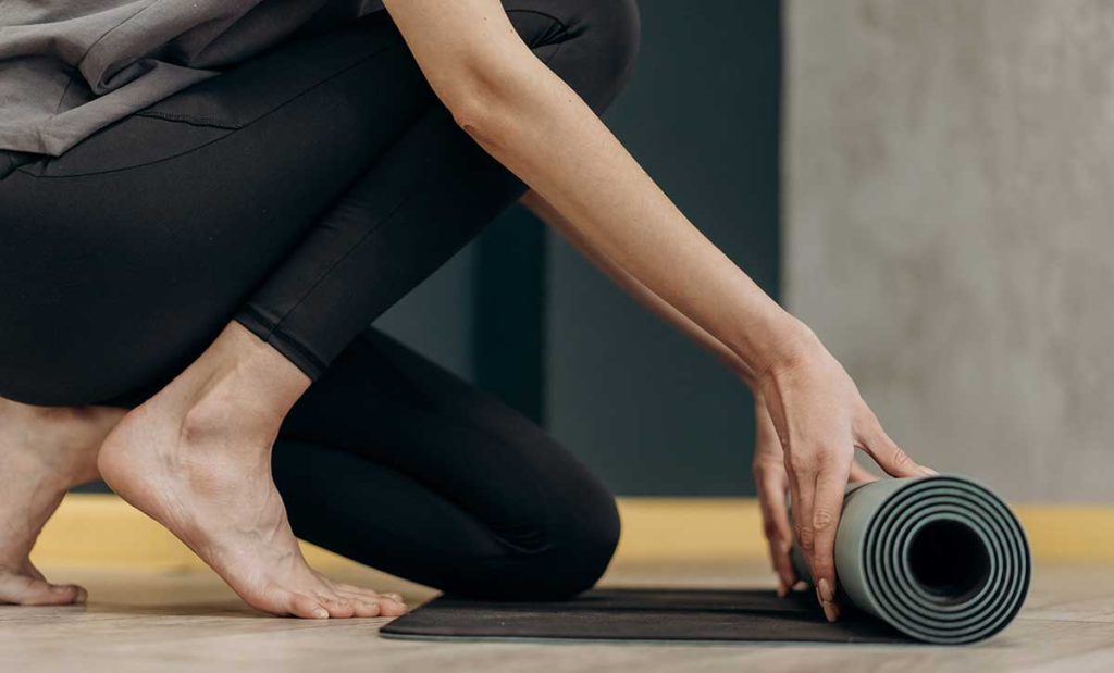 Woman unrolling a yoga mat. | Stopping MS