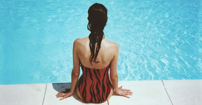 Woman sitting on edge of swimming pool.