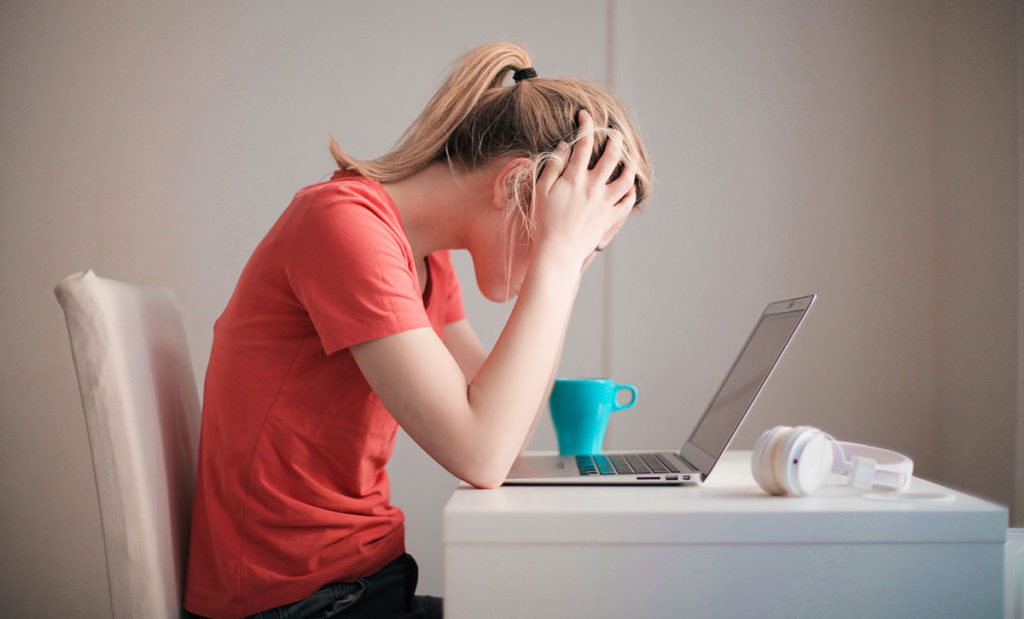 Young woman stressed while using laptop.