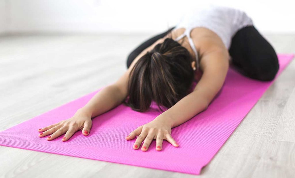 Woman stretching on a pink yoga mat.