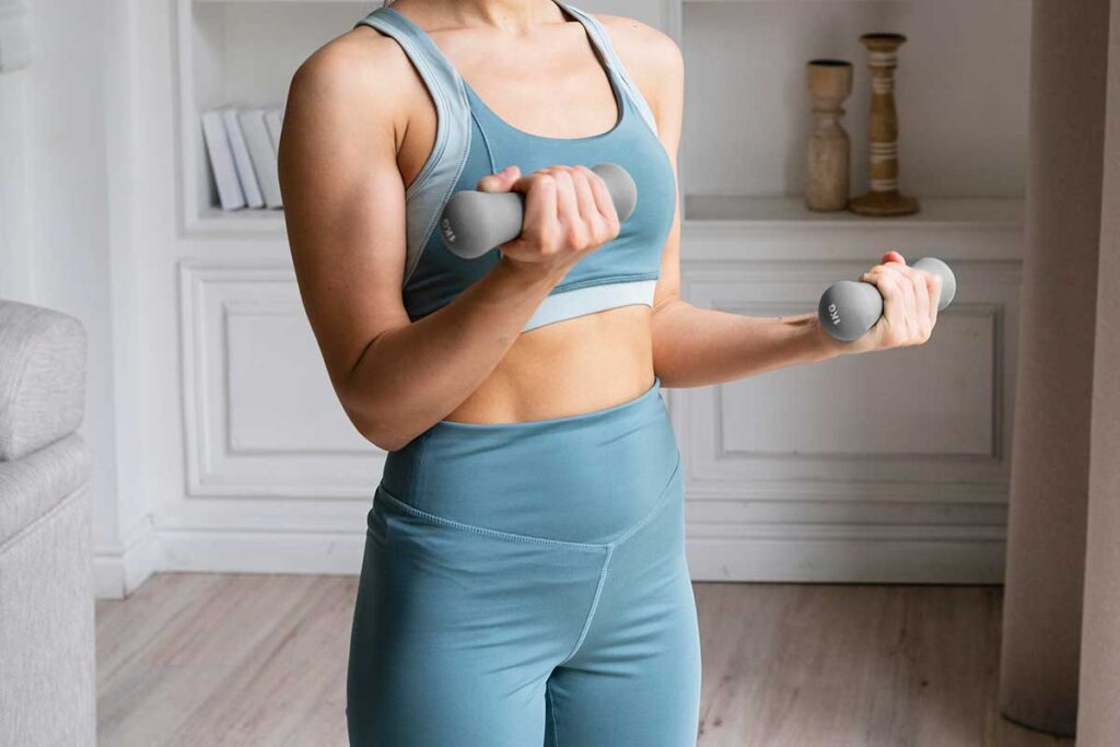 Woman lifting small weights at home.