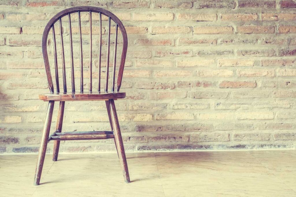 Wooden chair with light brick background.