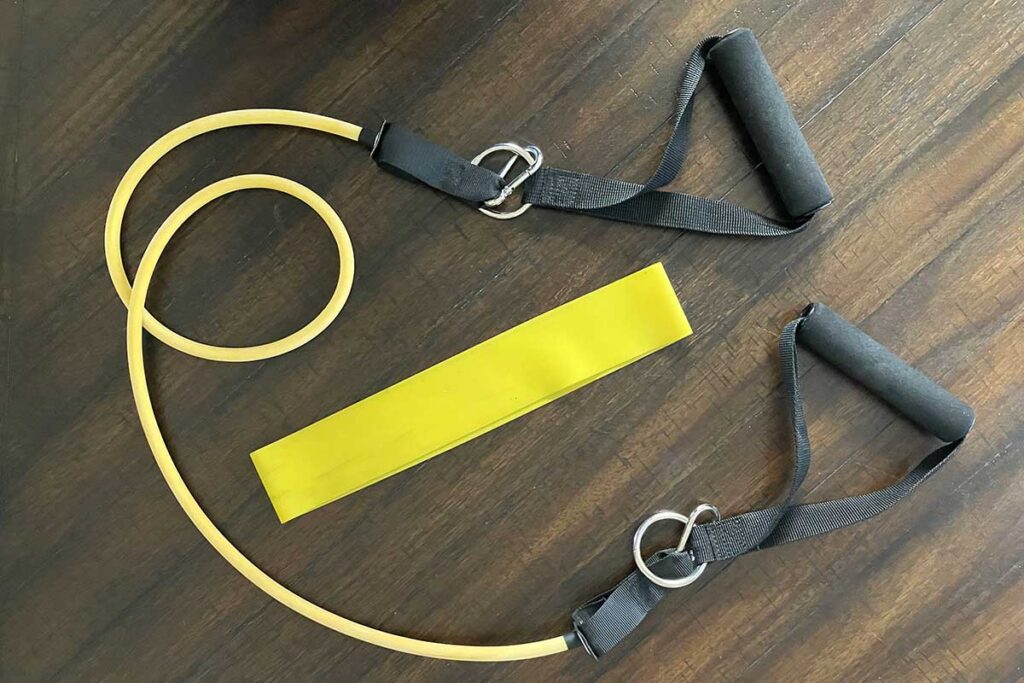 Yellow resistance band and yellow loop band on dark hardwood floor.