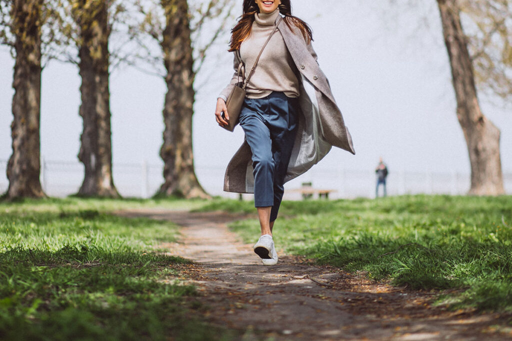 Happy young woman walking on trail in a park.