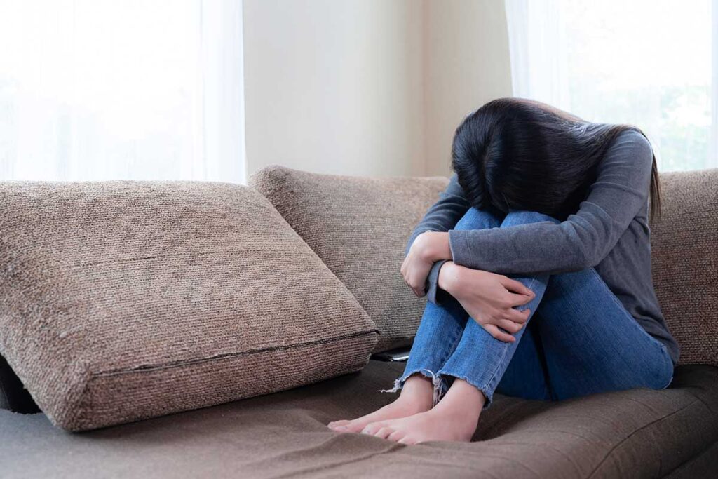 Young woman depressed on sofa.