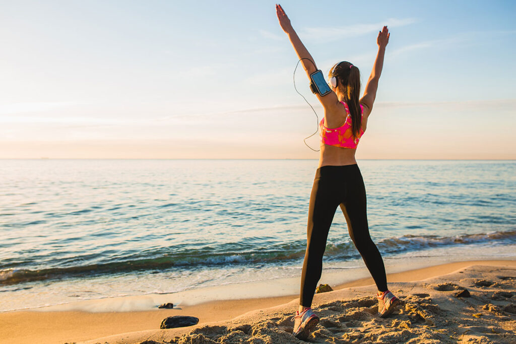 Young woman doing exercises on the beach in morning. 