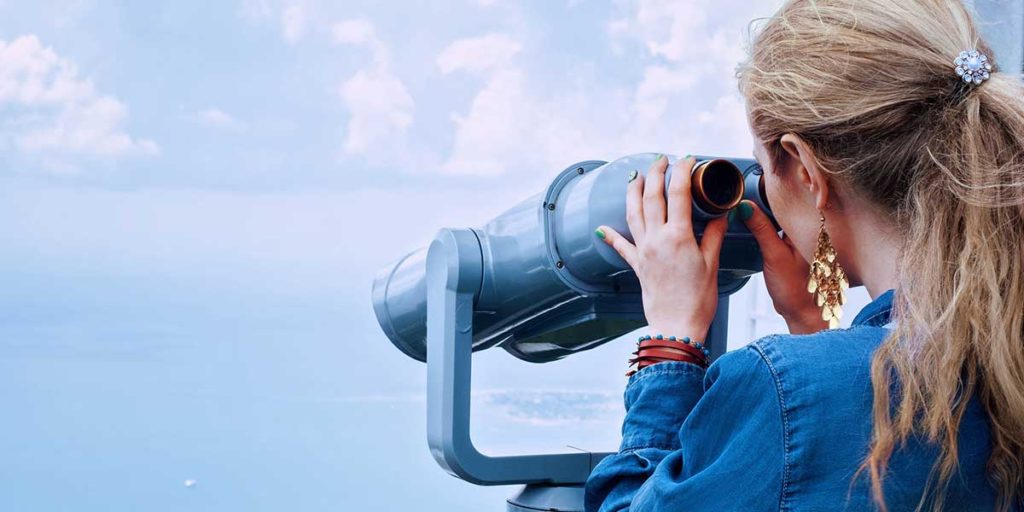 Young woman looking through binoculars.