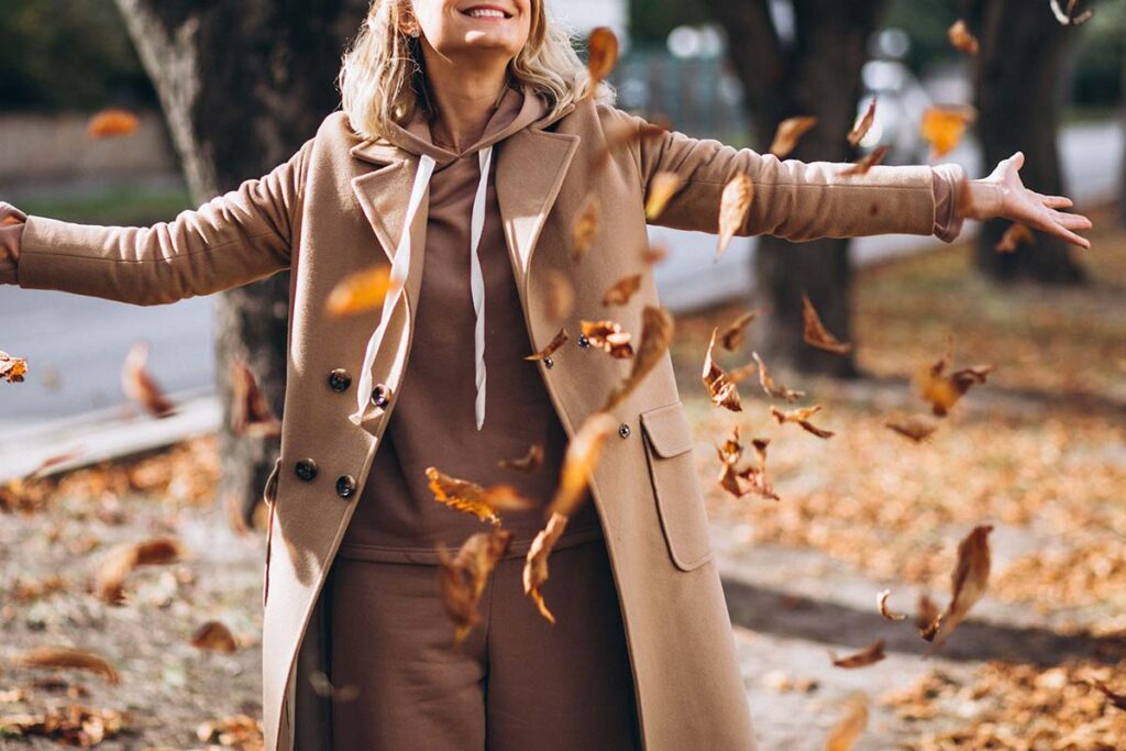 Young woman tossing autumn leaves into the air.