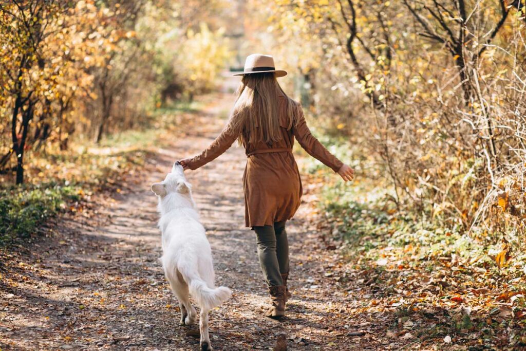 Young woman in park with her white dog.