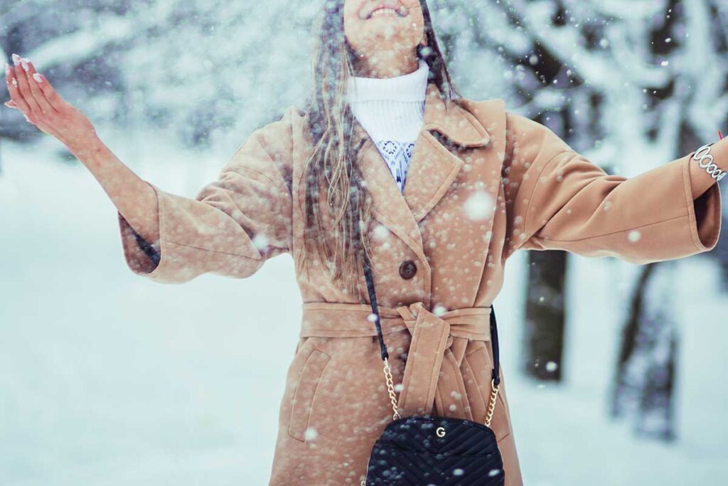 Young woman with long hair playing with snow.