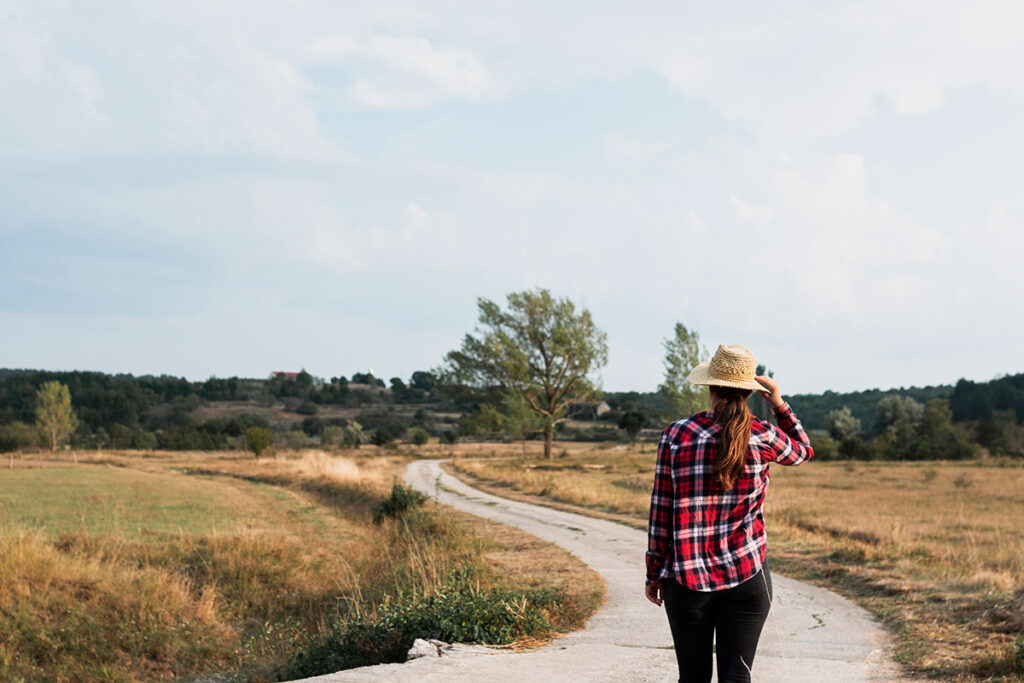 Young woman walking on an old curvy country road.