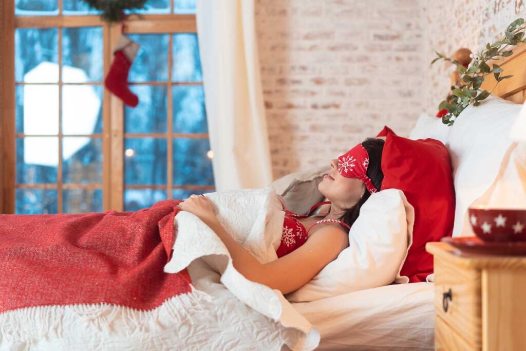 Young woman sleeping in her bed with  a red and white snowflake mask.