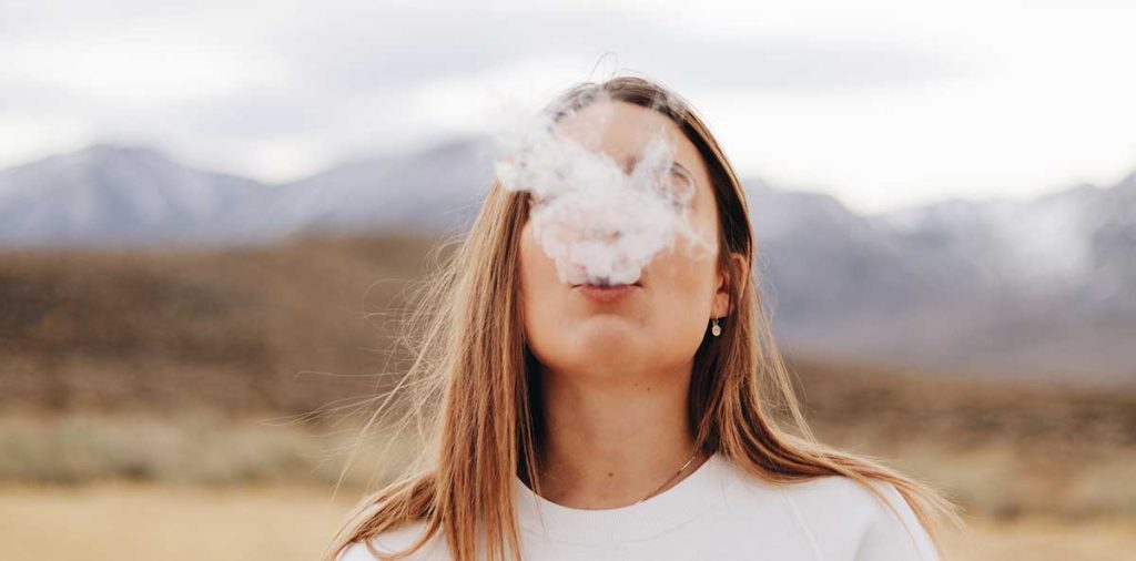 Young woman smoking with scenic background.