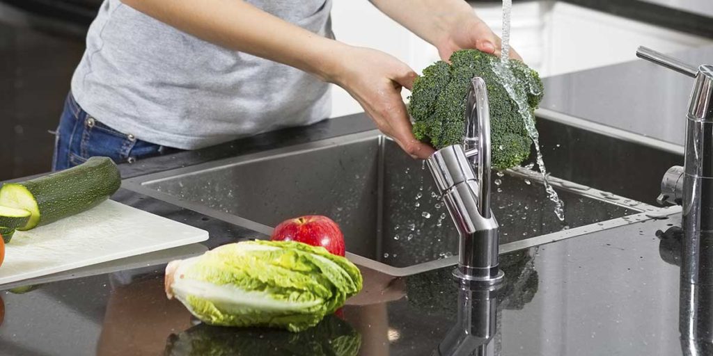 Young woman washing vegetables