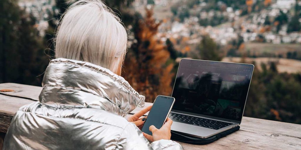 Young woman outdoors searching laptop and smart phone.