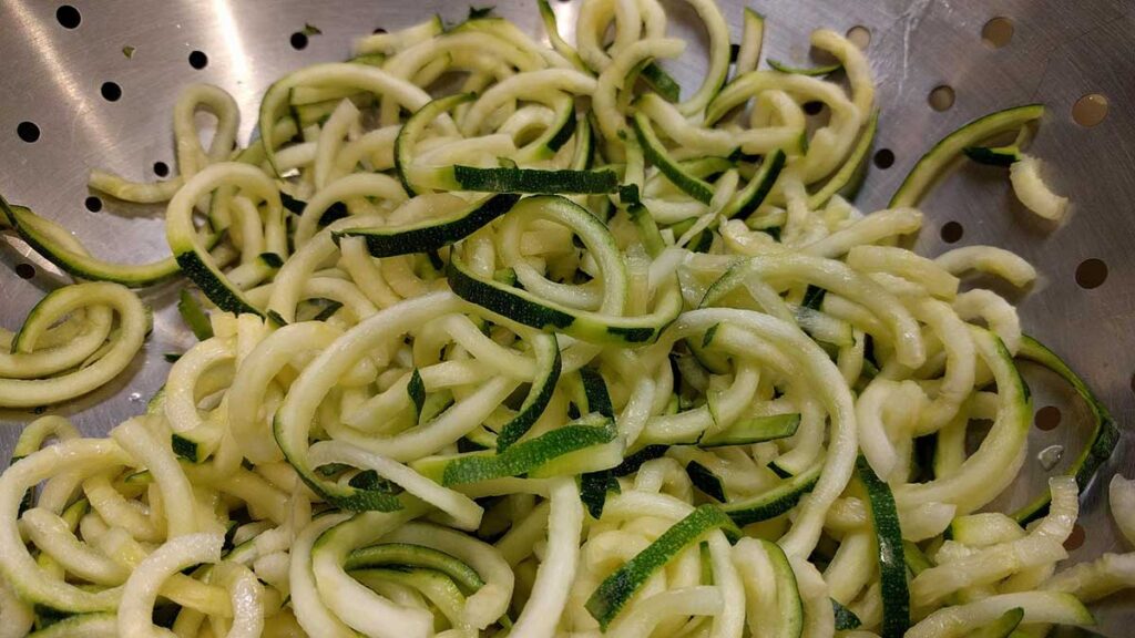 Zucchini noodles in a colander.